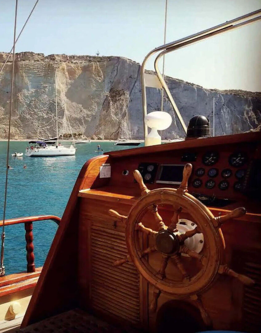 Traditional Greek gulet sailing near picturesque cliffs, showcasing the beauty of the Wooden Regatta Event in Athens by Events on Board.