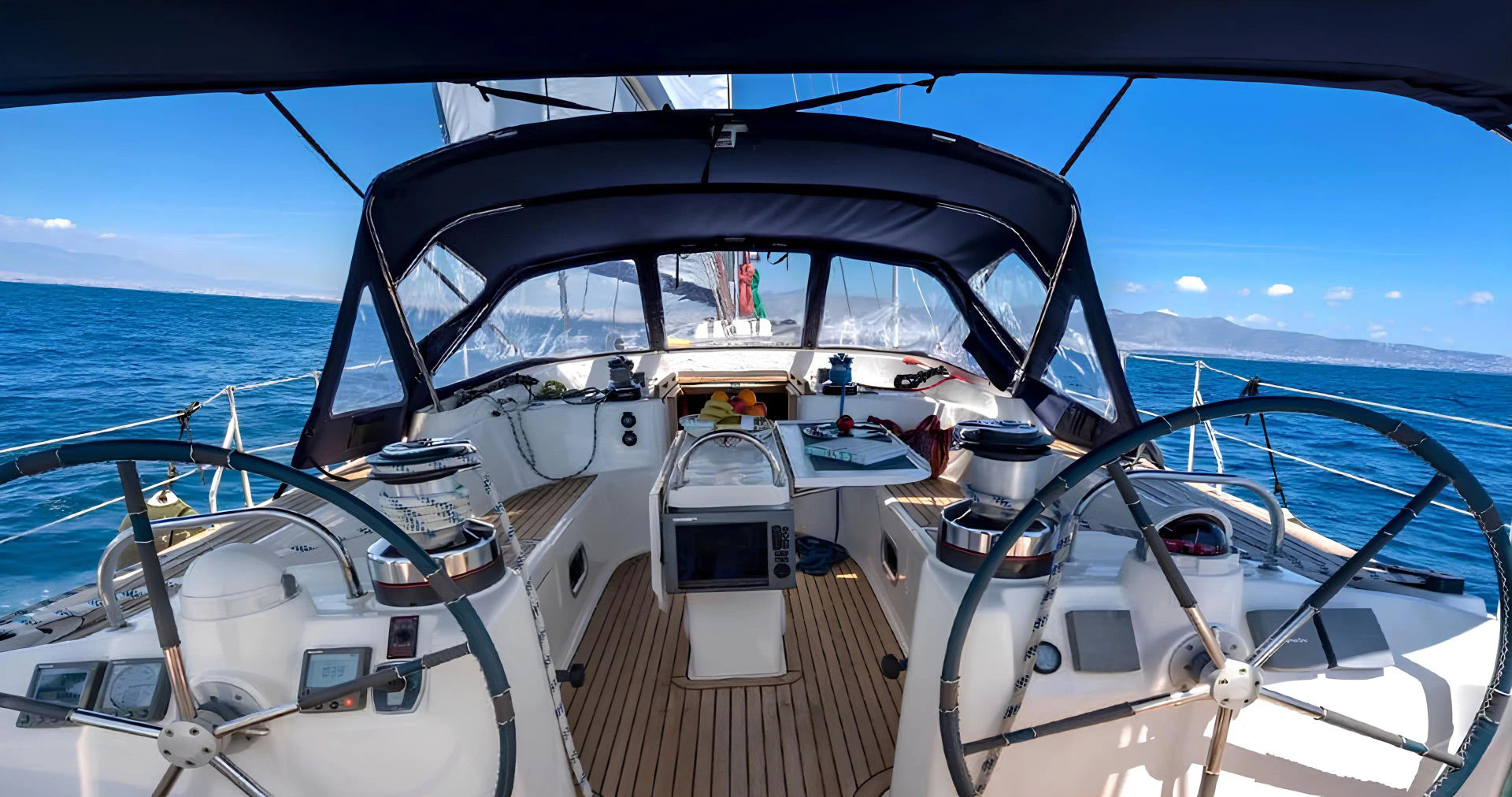 View from the cockpit of the Ocean Star 51.2, showing the yacht's steering wheels and navigation equipment, part of the Mykonos sailing adventure by Events on Board.