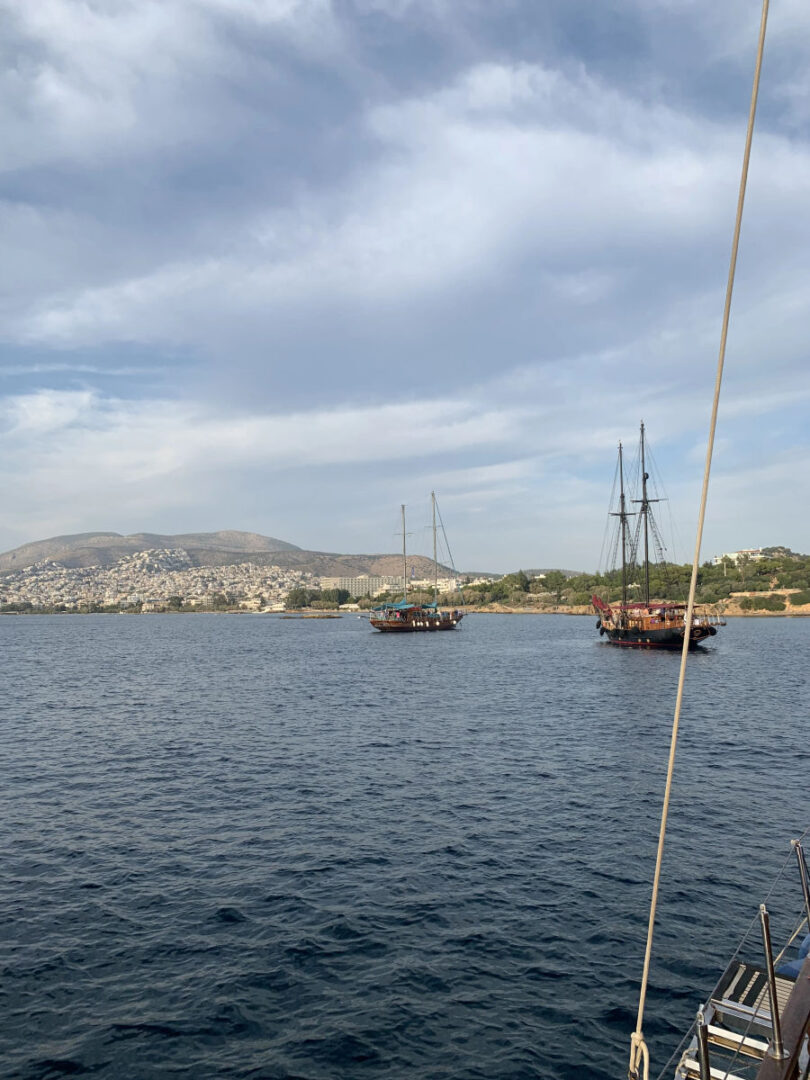 Multiple traditional Greek gulets sailing near Athens during the Wooden Regatta Event, showcasing the scenic coastline, by Events on Board.